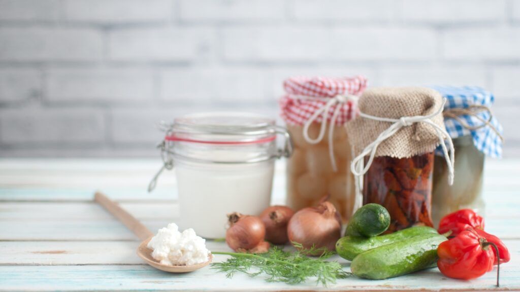 Variedad de alimentos fermentados caseros como kéfir, chucrut y vegetales encurtidos sobre mesa de madera, esenciales para restaurar la microbiota intestinal y mejorar la sensibilidad a la insulina.